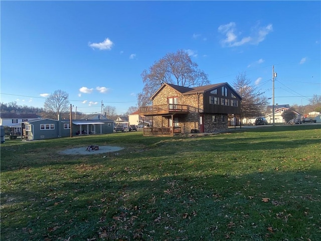 rear view of house featuring a yard, a fire pit, and a deck