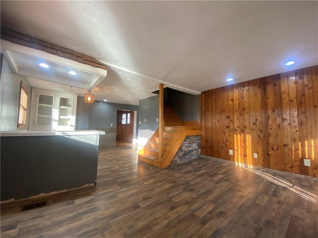 unfurnished living room with dark hardwood / wood-style floors and wood walls