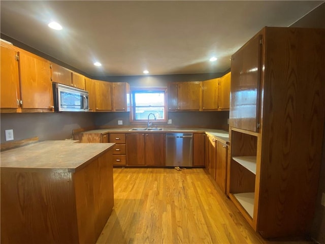 kitchen featuring kitchen peninsula, stainless steel appliances, light hardwood / wood-style flooring, and sink