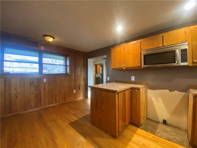 kitchen with kitchen peninsula, light hardwood / wood-style flooring, and wood walls