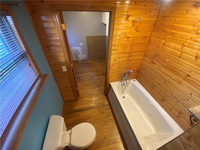 bathroom with hardwood / wood-style flooring, toilet, wood walls, and a bathing tub