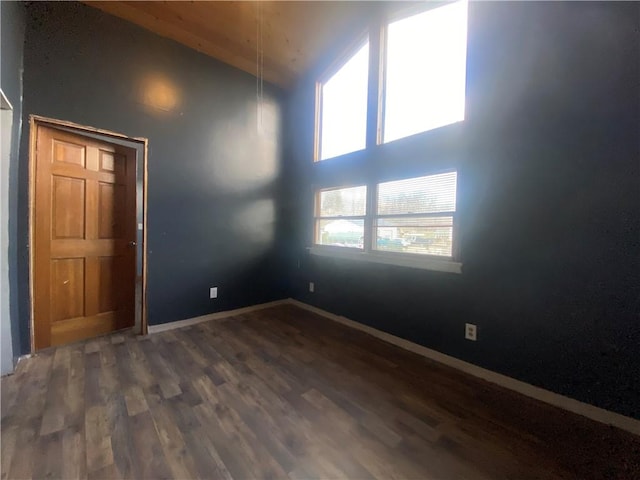 unfurnished room with high vaulted ceiling and dark wood-type flooring