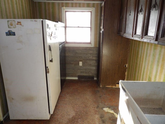 kitchen with wooden walls, dark brown cabinets, and white refrigerator