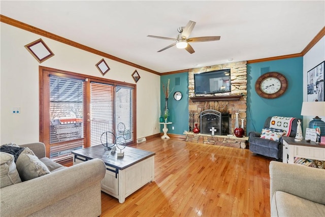 living room with ceiling fan, a fireplace, wood-type flooring, and ornamental molding