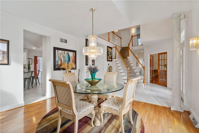 dining space featuring a chandelier, light wood-type flooring, and decorative columns