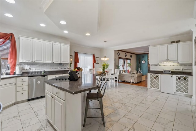 kitchen with tasteful backsplash, white cabinetry, stainless steel dishwasher, and decorative light fixtures