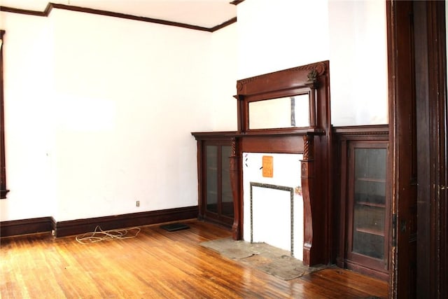 unfurnished living room with wood-type flooring and ornamental molding