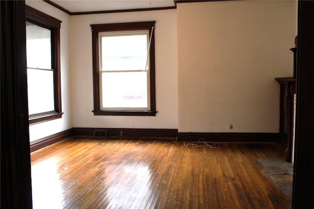 unfurnished living room with wood-type flooring, ornamental molding, and a healthy amount of sunlight