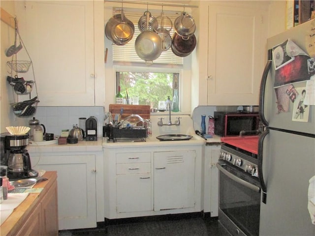 kitchen with decorative backsplash, appliances with stainless steel finishes, white cabinetry, and sink