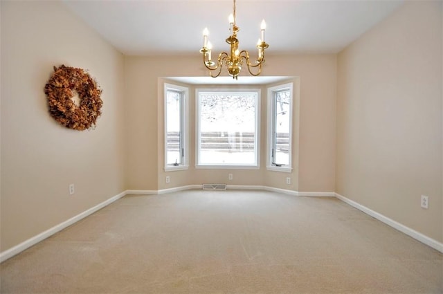 spare room with carpet floors and a notable chandelier