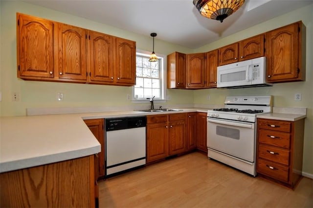 kitchen featuring light hardwood / wood-style floors, sink, white appliances, and hanging light fixtures