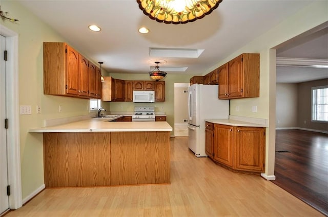 kitchen featuring sink, white appliances, light hardwood / wood-style flooring, and kitchen peninsula