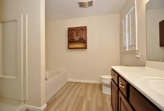 bathroom with toilet, a tub to relax in, hardwood / wood-style flooring, and vanity