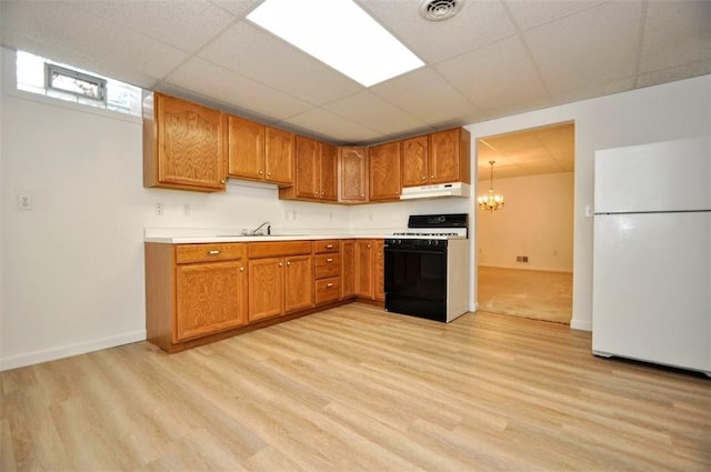 kitchen with a notable chandelier, light hardwood / wood-style floors, sink, range with gas stovetop, and white refrigerator