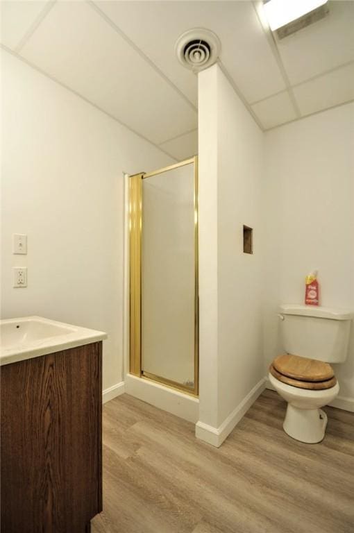 bathroom featuring hardwood / wood-style floors, an enclosed shower, vanity, toilet, and a drop ceiling