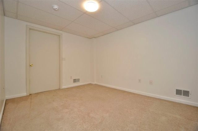 carpeted empty room featuring a drop ceiling