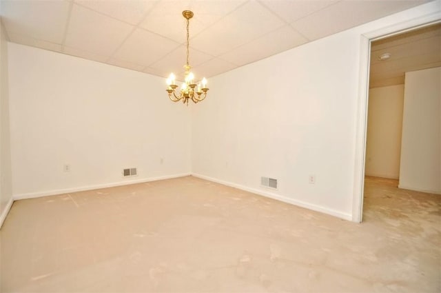 spare room featuring a paneled ceiling, carpet flooring, and a chandelier