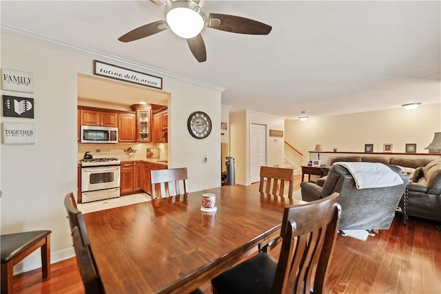 dining space with wood-type flooring, ceiling fan, and crown molding