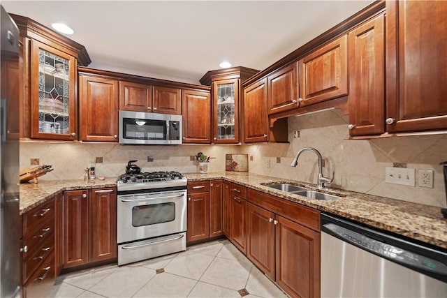 kitchen with sink, stainless steel appliances, tasteful backsplash, light stone counters, and light tile patterned flooring