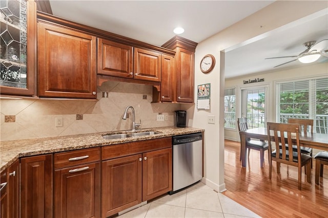 kitchen with light stone countertops, sink, stainless steel dishwasher, decorative backsplash, and light wood-type flooring