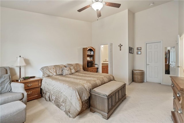 bedroom featuring ensuite bath, ceiling fan, a towering ceiling, and light carpet