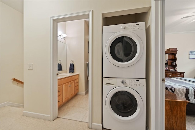 laundry room with sink, light tile patterned floors, stacked washer and clothes dryer, and ornamental molding