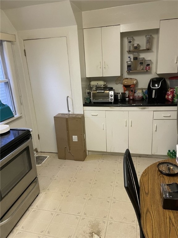 kitchen with stainless steel electric stove and white cabinetry