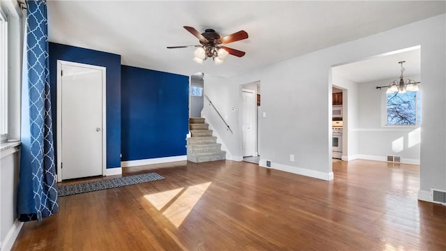 interior space with ceiling fan with notable chandelier and hardwood / wood-style flooring