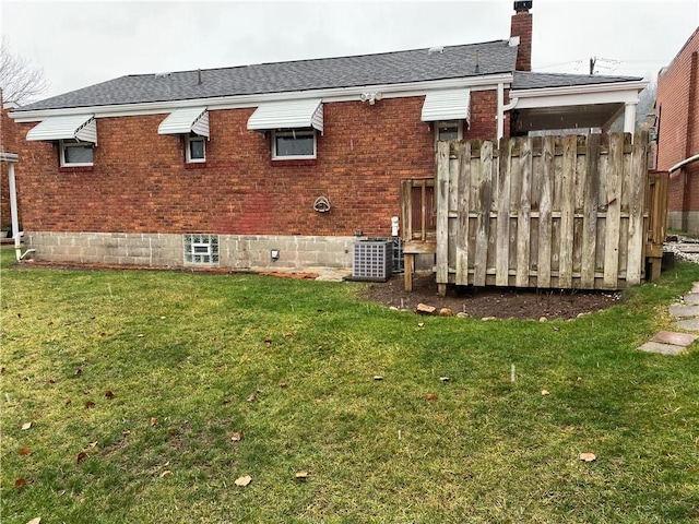 rear view of property featuring a yard and central air condition unit