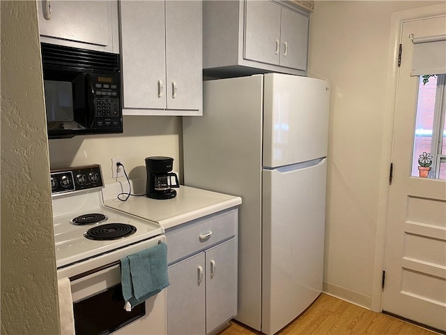 kitchen with gray cabinets, light hardwood / wood-style floors, and white appliances