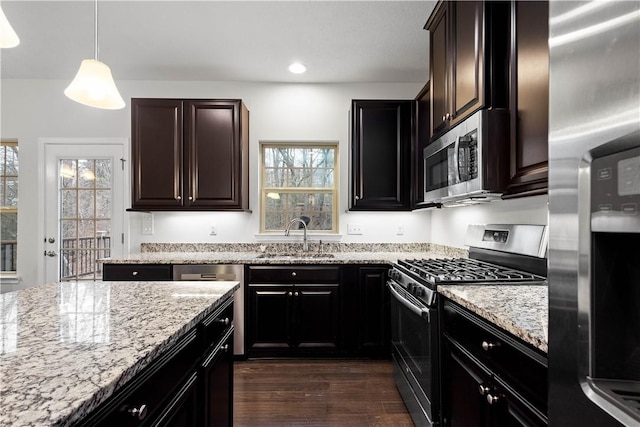 kitchen featuring pendant lighting, dark wood-type flooring, sink, appliances with stainless steel finishes, and light stone counters