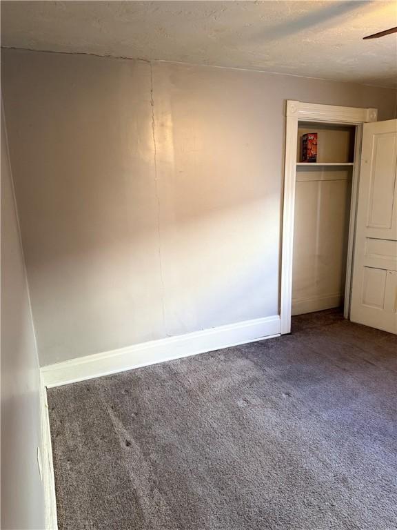 unfurnished bedroom featuring a textured ceiling, carpet floors, and a closet