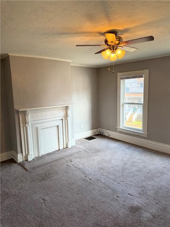 unfurnished living room featuring ceiling fan, a fireplace, carpet, and ornamental molding