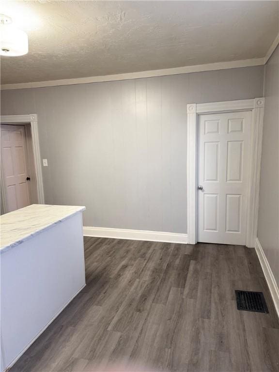 spare room featuring ornamental molding and dark wood-type flooring