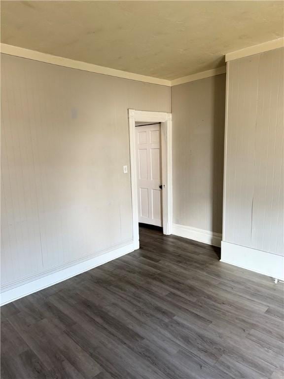 spare room featuring dark hardwood / wood-style floors and crown molding