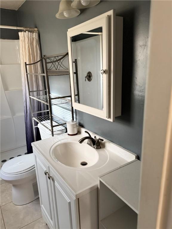 bathroom featuring toilet, tile patterned flooring, vanity, and walk in shower