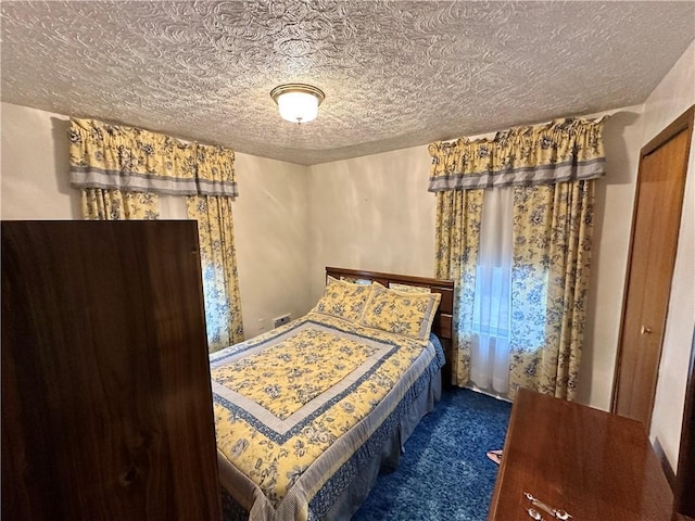 bedroom with dark colored carpet, a textured ceiling, and a closet