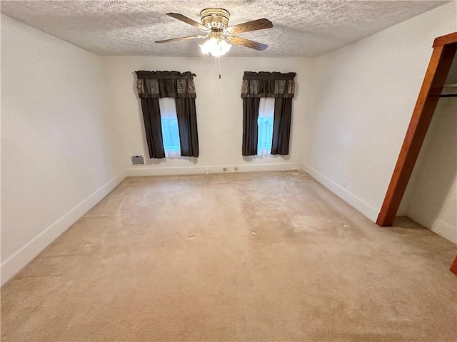 spare room with a textured ceiling, ceiling fan, and light carpet