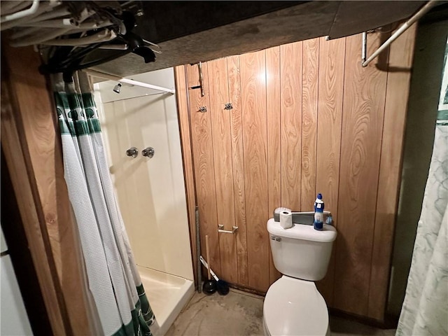 bathroom with wood walls, toilet, concrete floors, and walk in shower