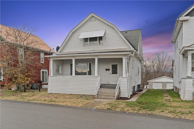 bungalow-style home with central AC unit, a garage, an outbuilding, and covered porch