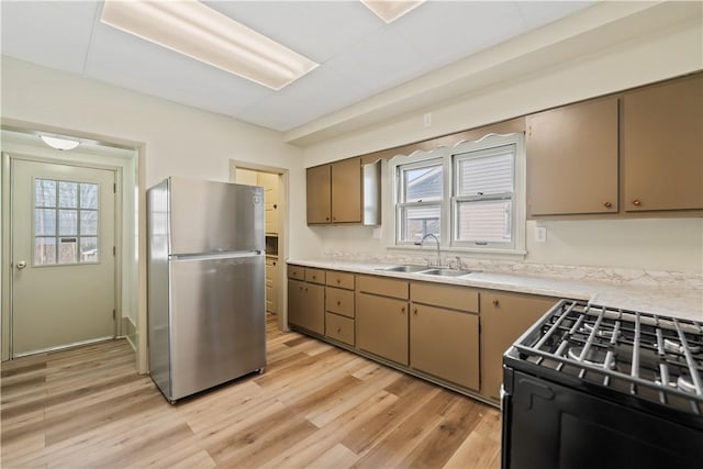 kitchen with light hardwood / wood-style flooring, electric stove, stainless steel refrigerator, and sink