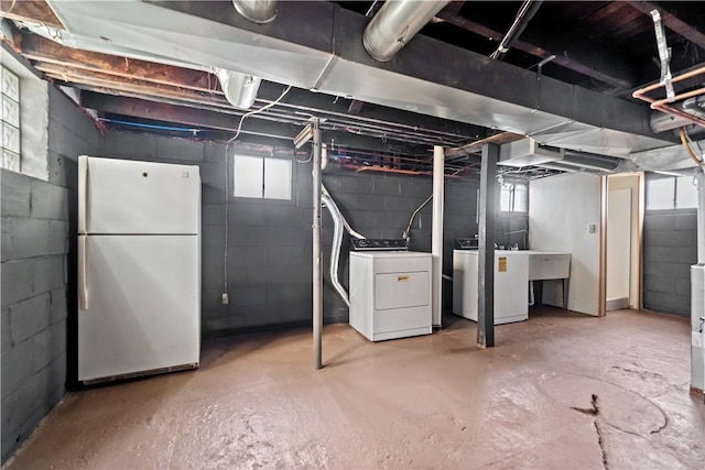 basement featuring white refrigerator and washing machine and clothes dryer