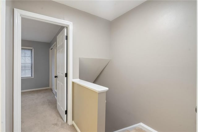 corridor with baseboards, an upstairs landing, and light colored carpet