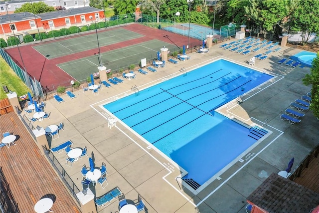 view of swimming pool featuring a tennis court, a patio area, and fence