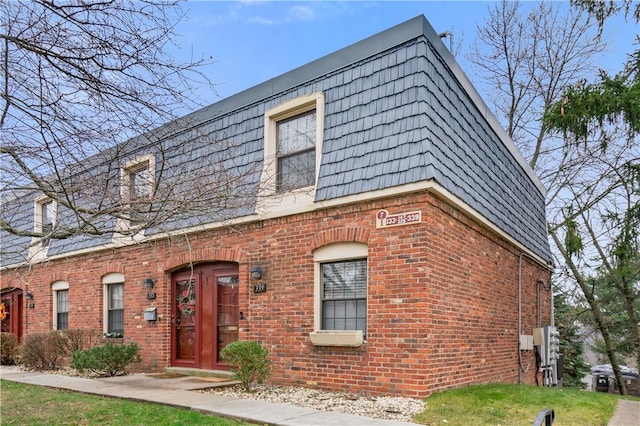 view of front of home with brick siding and mansard roof