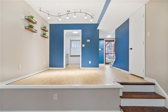 interior space featuring rail lighting, baseboards, and wood finished floors