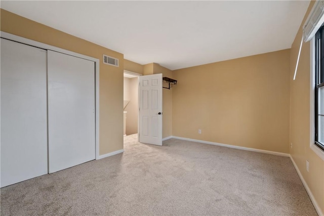 unfurnished bedroom featuring carpet, a closet, visible vents, and baseboards