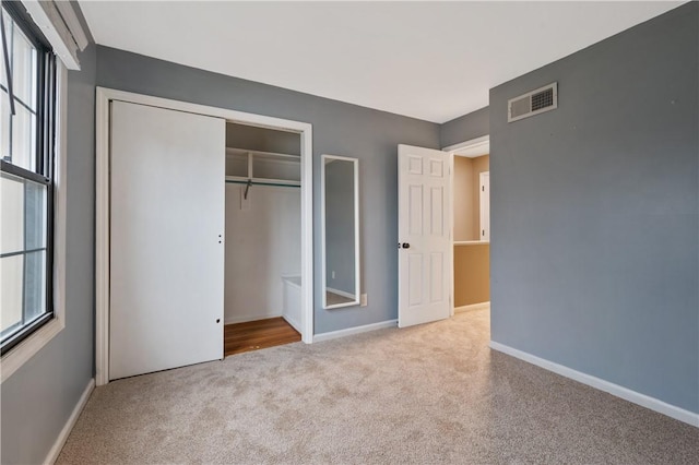 unfurnished bedroom with carpet floors, a closet, visible vents, and baseboards