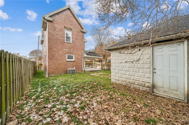 rear view of house featuring central air condition unit and a yard