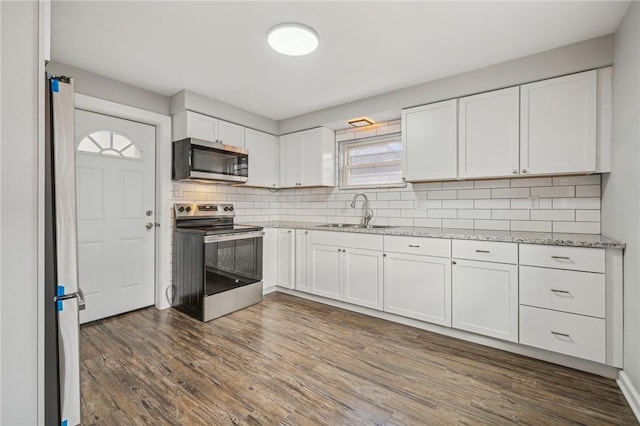 kitchen with white cabinets, sink, dark hardwood / wood-style floors, appliances with stainless steel finishes, and tasteful backsplash